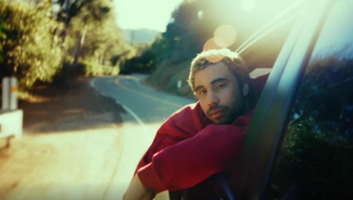 A man leans from a car window on a canyon road at golden hour