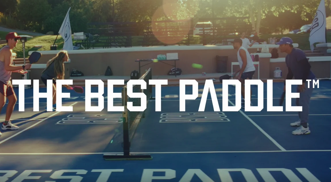 Pickleball rally on a blue court at golden hour